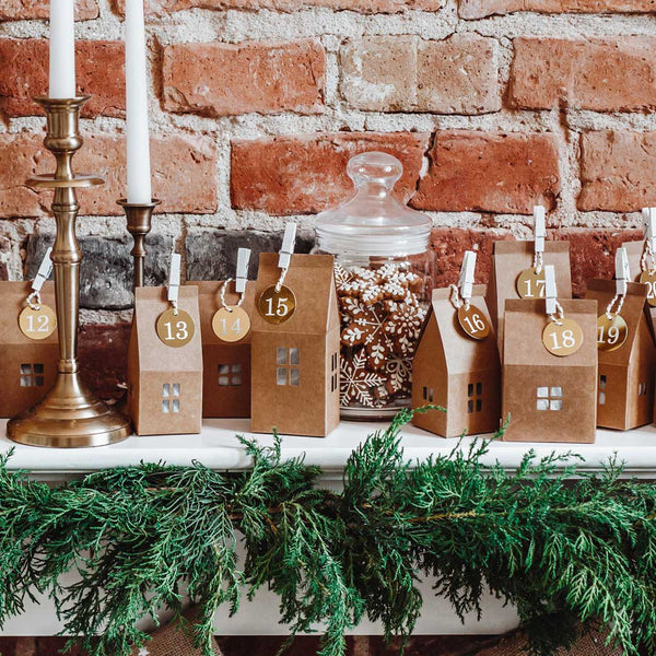 Calendario de Adviento con casitas de papel kraft y etiquetas doradas