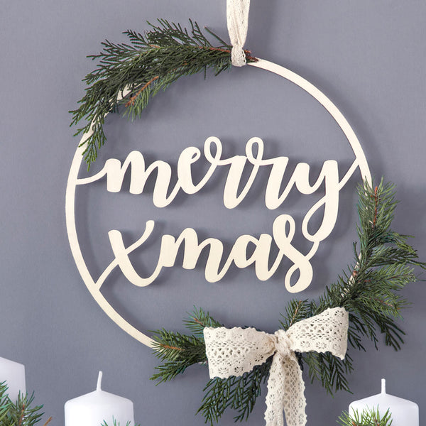 Colgante de madera con texto Merry Xmas colgado en pared blanca