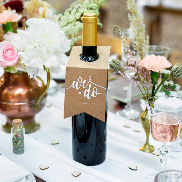 Colgadores de papel kraft con inscripción blanca We Do. Pack de 10 unidades para decoración de botellas en bodas.