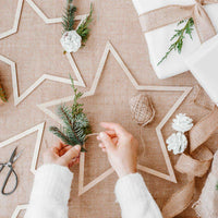 Estrella de madera colgante, parte del set de 3 unidades en mesa navideña. Decoración natural para fiestas y eventos.