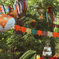 Guirnalda de hojas de papel de seda decorando una fiesta temática de animales del bosque