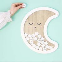Libro de firmas de madera con forma de luna y estrellas blancas, presentado como decoración en comunión o bautizo.