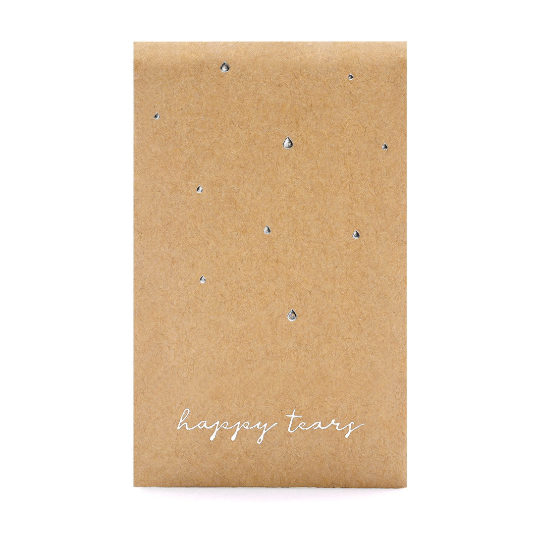 Detalle de sobres kraft con inscripción plateada “Happy Tears”, detalle de boda con pañuelos para lágrimas de felicidad.