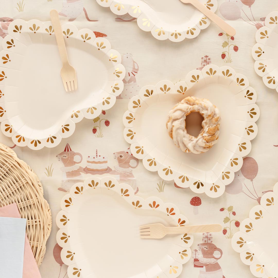 Mesa elegante de boda decorada con platos de papel con forma de corazón crema y dorado