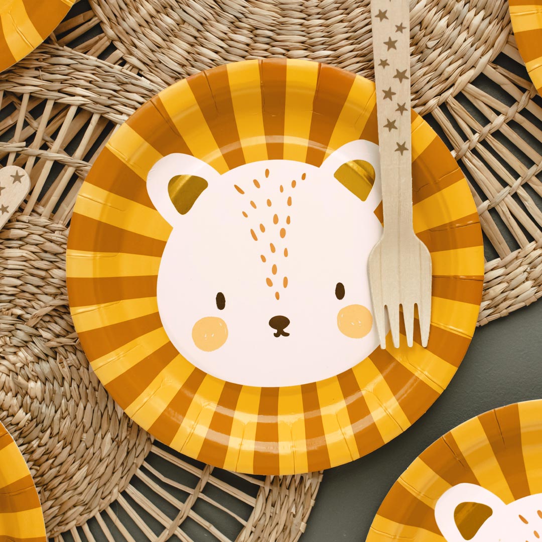 Mesa de fiesta temática safari decorada con platos de papel león Leo naranja y dorado