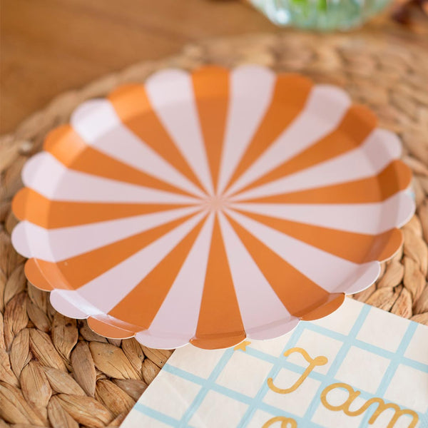 Mesa de cumpleaños con estética retro decorada con platos de papel a rayas rosa y dorado