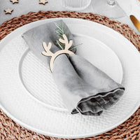 Servilletero de madera con cuernos de reno sobre mesa navideña