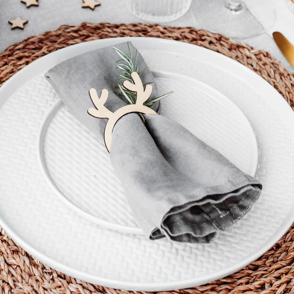 Servilletero de madera con cuernos de reno sobre mesa navideña
