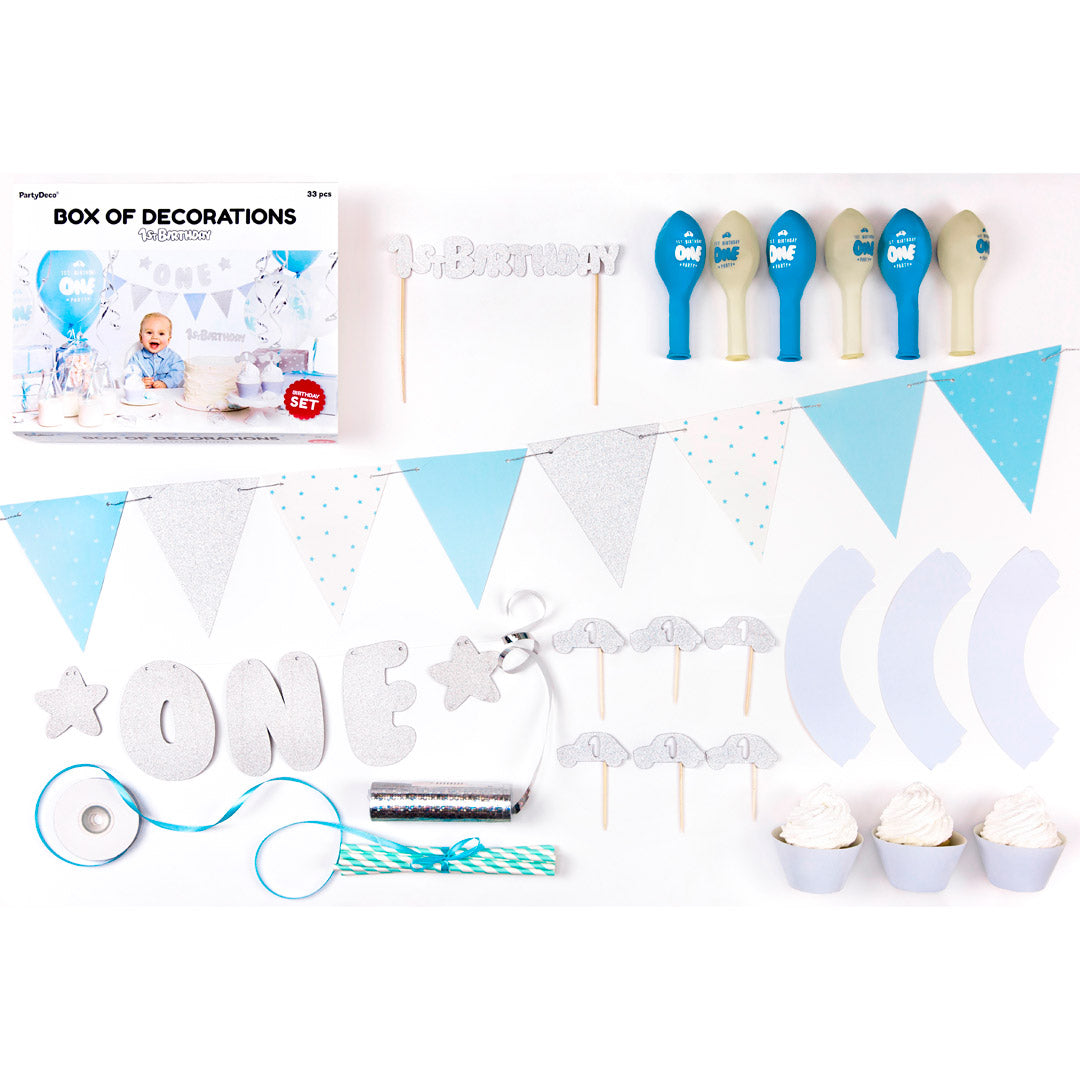 Detalle del set de decoraciones para primer cumpleaños en azul y plateado con globos, guirnalda y toppers.