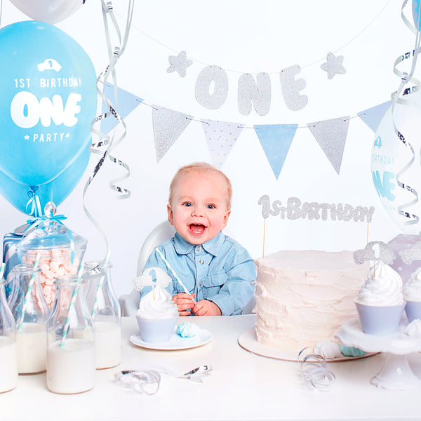 Set de decoraciones para primer cumpleaños en azul y plateado con globos, guirnalda y toppers.
