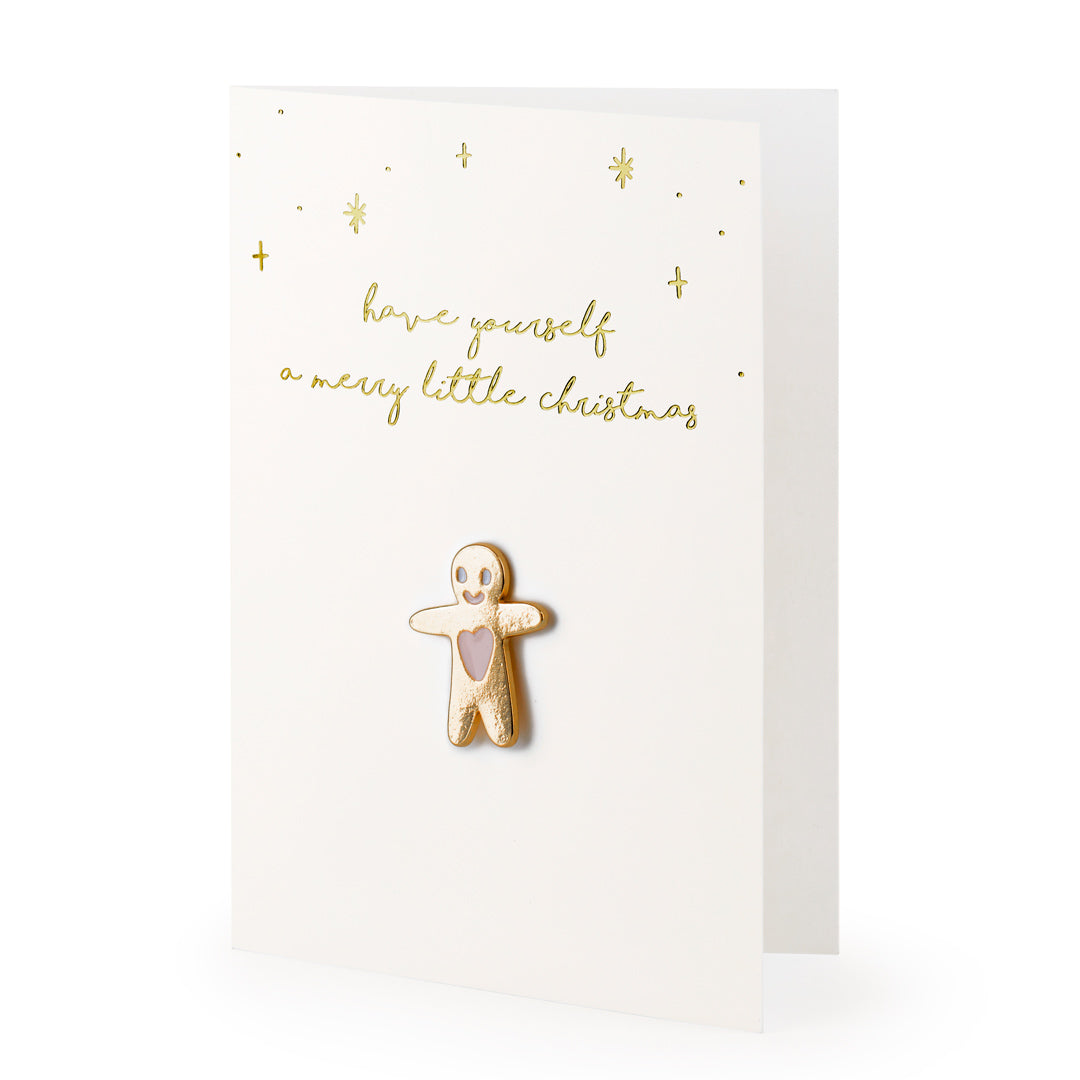 Detalle del pin de muñeco de jengibre sobre tarjeta dorada