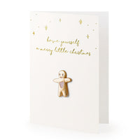 Detalle del pin de muñeco de jengibre sobre tarjeta dorada