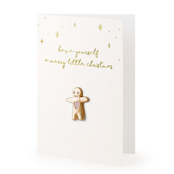 Detalle del pin de muñeco de jengibre sobre tarjeta dorada