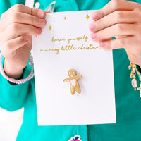 Tarjeta de Navidad blanca con pin de muñeco de jengibre dorado