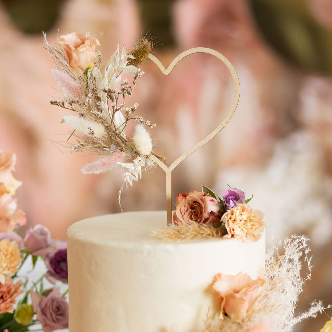 Topper de madera corazón decorando tarta de boda romántica con flores naturales