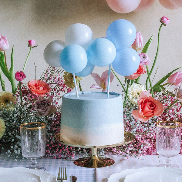 Topper de tarta de globos azul y blanco decorando tarta de baby shower