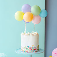 Topper de tarta de globos multicolor decorando tarta de cumpleaños colorida
