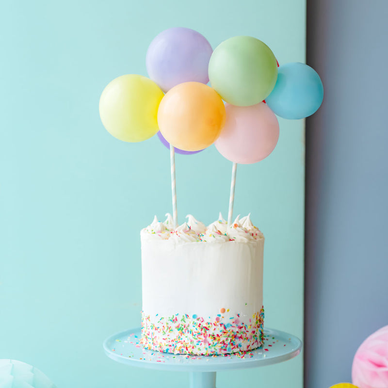 Topper de tarta de globos multicolor decorando tarta de cumpleaños colorida