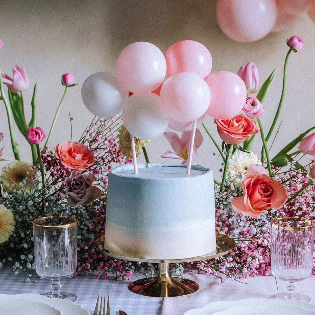 Topper de tarta de globos rosa y blanco decorando tarta de baby shower