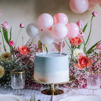 Topper de tarta de globos rosa y blanco decorando tarta de baby shower