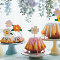 Toppers flores de colores decorando tarta de cumpleaños con estética floral y primaveral
