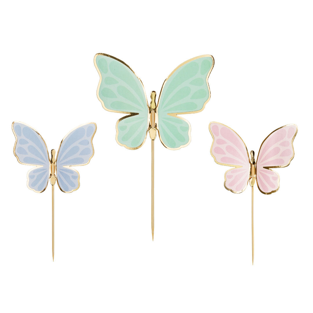 Detalle de los tres colores de toppers mariposas azul verde menta y rosa con bordes dorados brillantes