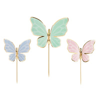 Detalle de los tres colores de toppers mariposas azul verde menta y rosa con bordes dorados brillantes