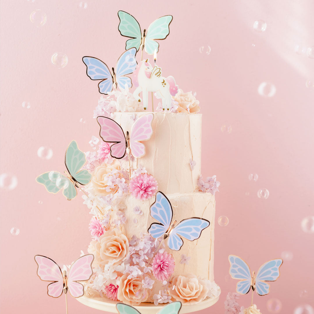 Toppers mariposas pastel y dorado decorando tarta de cumpleaños con estética primaveral