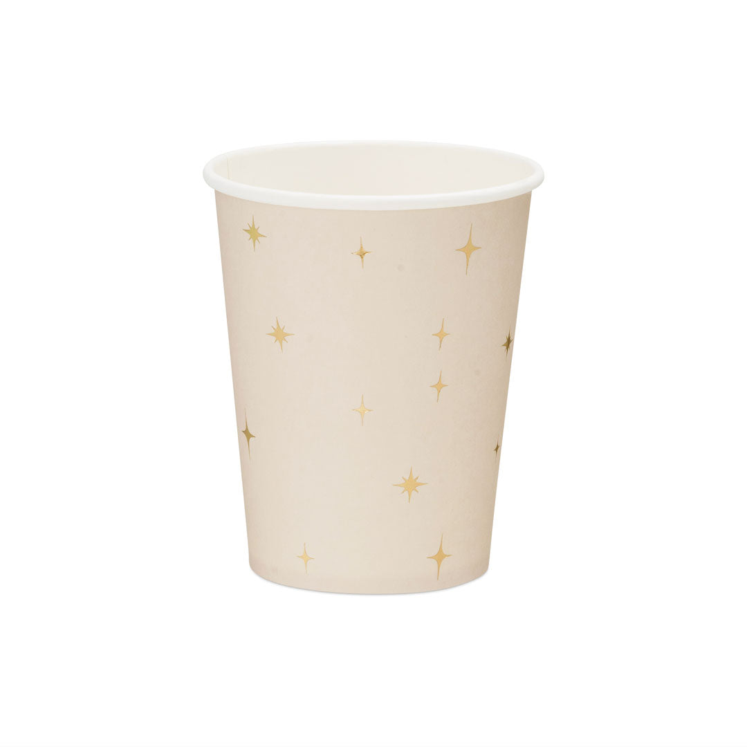 Detalle de las estrellas doradas de cuatro puntas sobre vaso de papel beige rosado