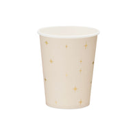 Detalle de las estrellas doradas de cuatro puntas sobre vaso de papel beige rosado