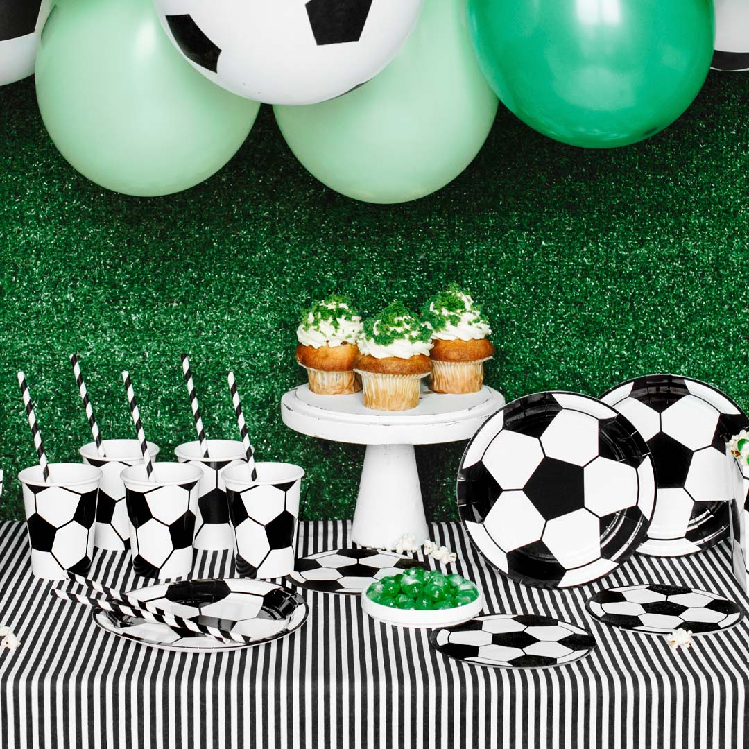Mesa de cumpleaños infantil temático de fútbol decorada con vasos de papel balón