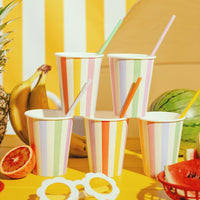 Mesa de cumpleaños colorida decorada con vasos de papel a rayas en colores pastel
