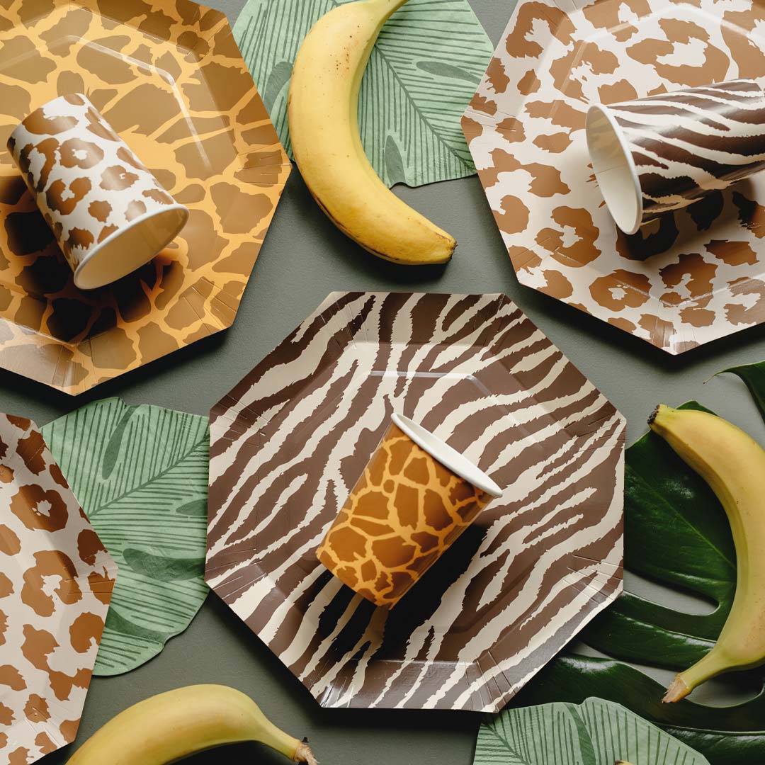 Mesa de fiesta temática safari decorada con vasos de papel con estampados de animales