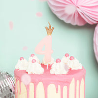 Vela de cumpleaños con número rosa y corona dorada decorando tarta de cumpleaños infantil
