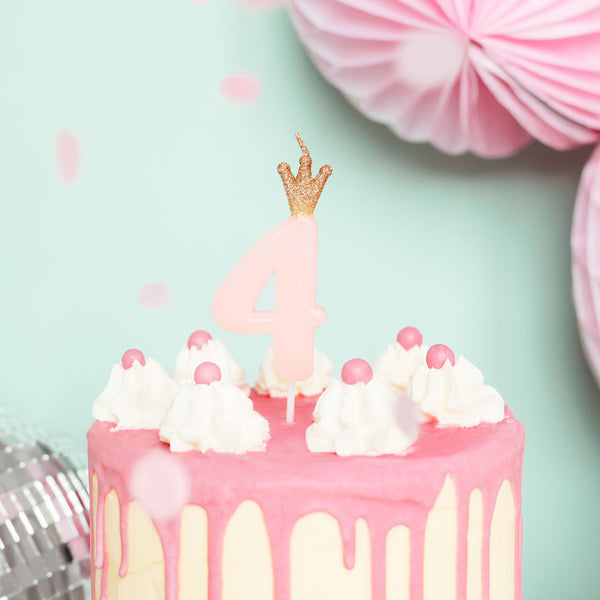 Vela de cumpleaños con número rosa y corona dorada decorando tarta de cumpleaños infantil