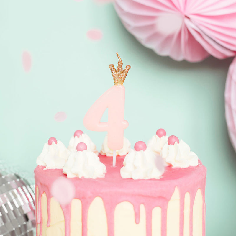 Vela de cumpleaños con número rosa y corona dorada decorando tarta de cumpleaños infantil