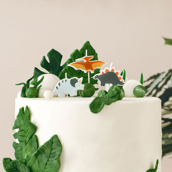 Velas de cumpleaños dinosaurios decorando tarta de cumpleaños temática prehistórica