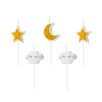 detalle de las velas de cumpleaños con forma de luna, estrellas y nubes en blanco y dorado